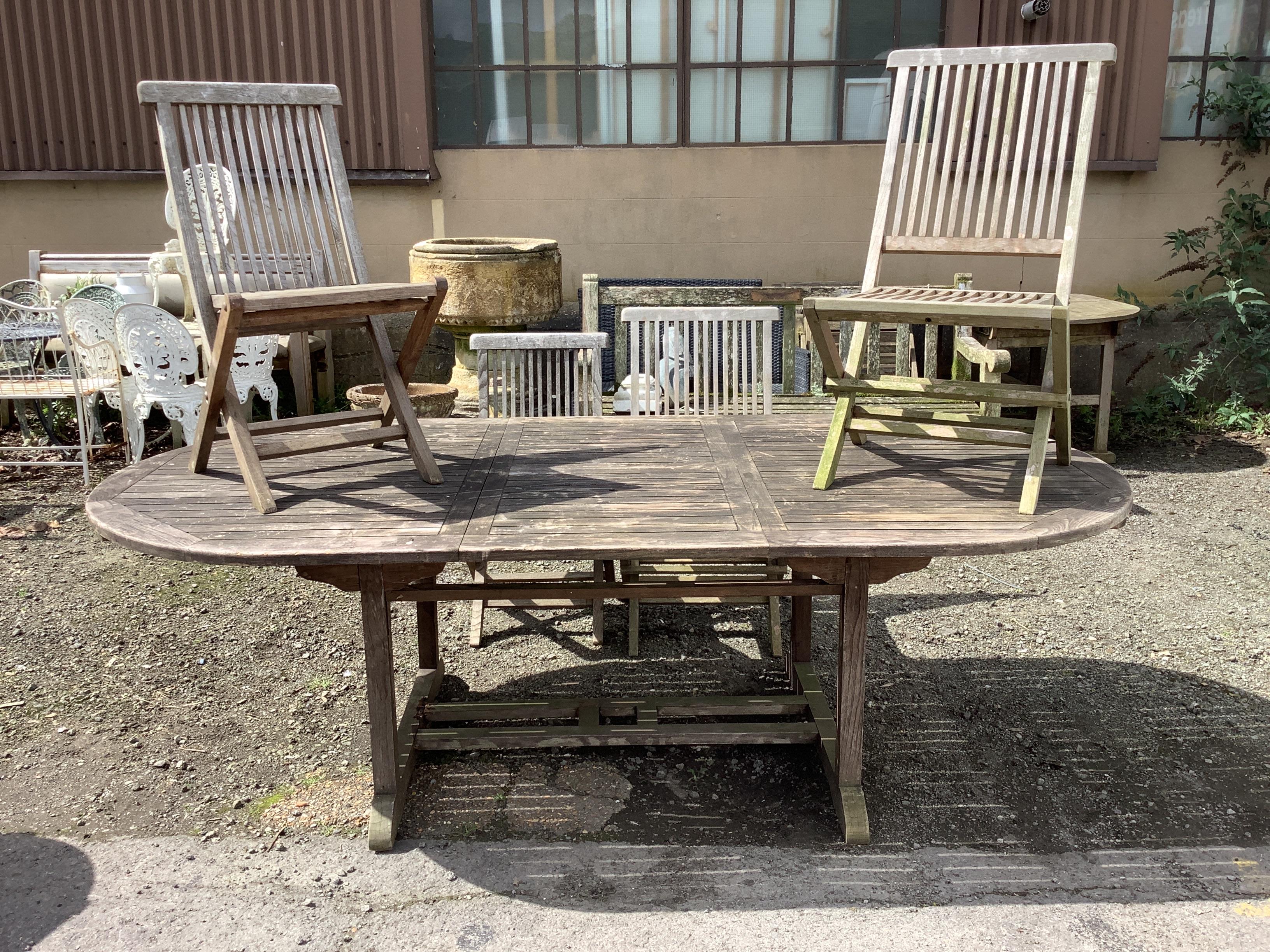 A weathered teak extending garden table, 240cm extended, depth 120cm, height 73cm, together with four folding chairs, (two with arms)